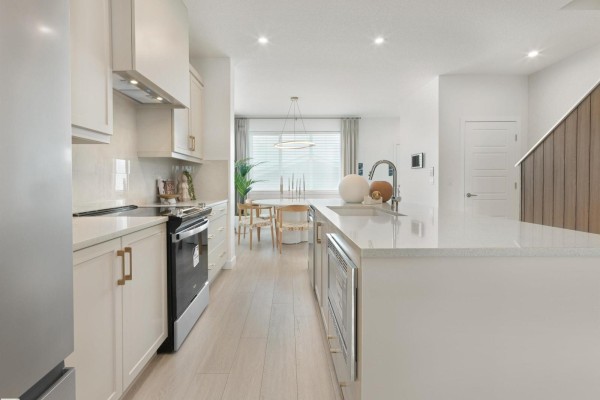 Kitchen with white cabinets, quartz countertops, stainless steel appliances, and a view of a dining area. - 350 Stiles Wy, Leduc
