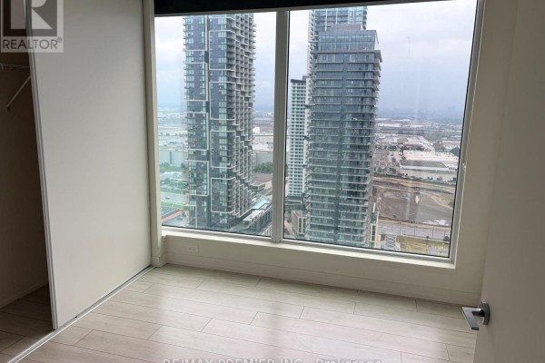 Empty bedroom with large windows showcasing city skyscrapers and light wood-look floors. - 3502 - 5 Buttermill Avenue, Vaughan