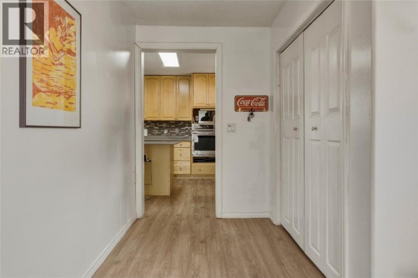 Hallway with a closet, Coca-Cola key holder, and an open doorway to the kitchen. - 3503 19 Street, Vernon
