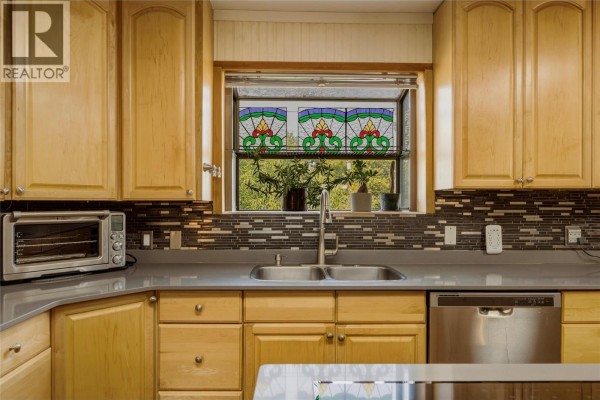 Kitchen counter with a double sink, stainless steel dishwasher, and light wood cabinets. - 3503 19 Street, Vernon