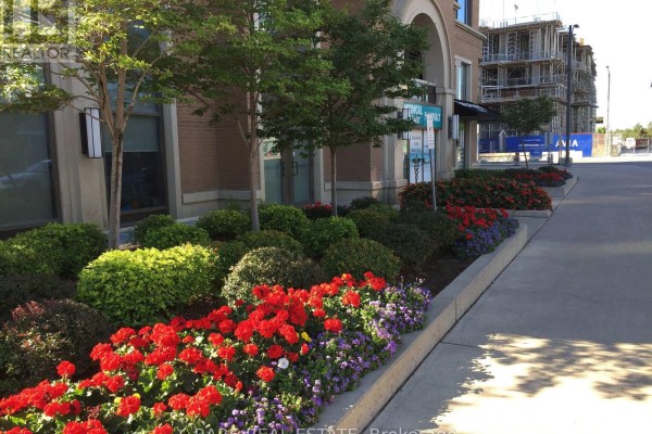Flower beds with red and purple flowers and green bushes along a concrete sidewalk. - 3505 - 385 Prince Of Wales Drive, Mississauga