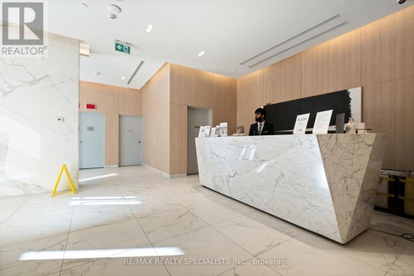 Lobby with a modern geometric marble reception desk and wood-paneled walls. - 3505 - 50 Ordnance Street, Toronto