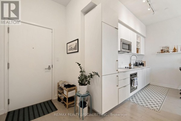 White kitchen with handleless cabinets, stainless steel appliances, and patterned rug. - 3505 - 50 Ordnance Street, Toronto
