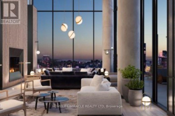Living room with fireplace, sofas, large windows, and city view at twilight. - 3505 - 55 Charles Street E, Toronto