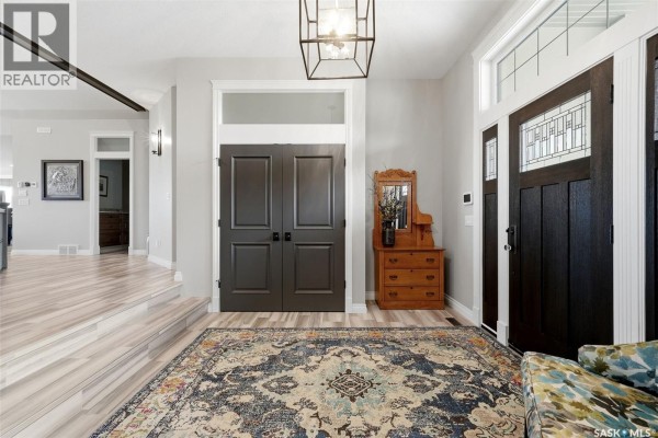 Covered front porch with stone pillars, a tiled floor, and a view of the street with houses and blue sky. - 3505 Green Brook Road, Regina