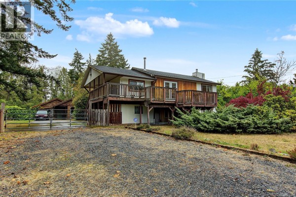 View of the house from the driveway, showing a detached garage and fence. - 3505 Harris Cres, Qualicum Beach