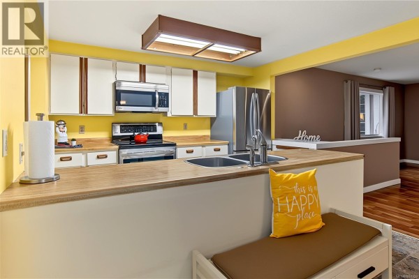 Kitchen with white cabinets, stainless steel appliances, and light wood countertops. - 3505 Harris Cres, Qualicum Beach