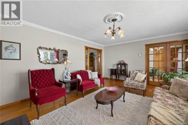 Open-concept living area with kitchen, dining island, and sliding glass doors. - 3507 Rue De L'anse, Tracadie