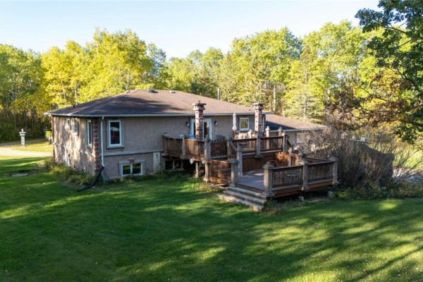 Back of the house featuring a large wooden deck with multiple levels. - 35091 Gueret 44e Road, La Broquerie