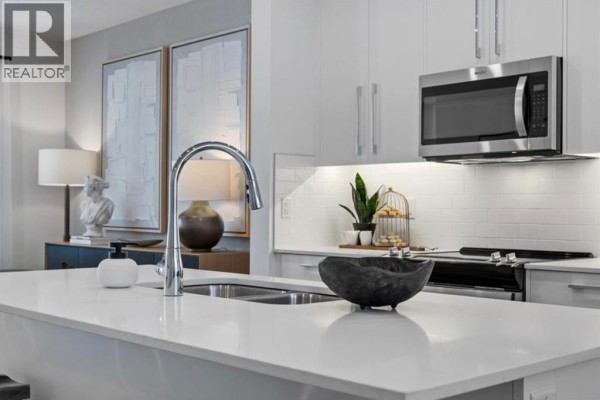 Close-up of kitchen island with faucet, sink, and decorative bowl, showing white subway tile backsplash. - 351, 141 Prince Court, Rural Rocky View County