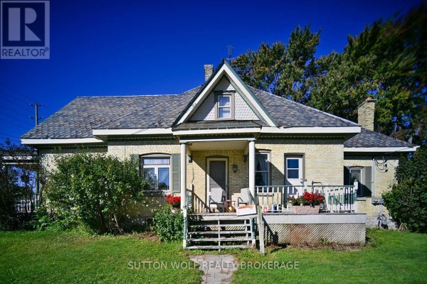 Front exterior of a yellow brick house with a covered porch, shutters, and a peaked roof. - 351 Albert Street, Strathroy Caradoc