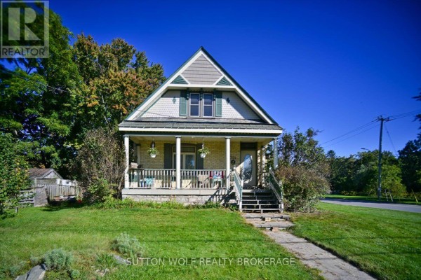 Front exterior of a yellow brick house featuring a covered porch, gable roof, and surrounding green lawn. - 351 Albert Street, Strathroy Caradoc