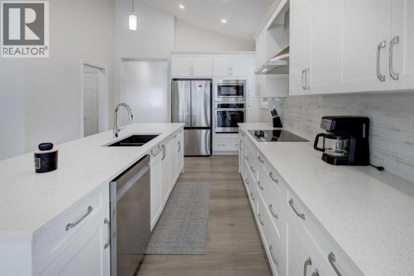 Spacious white kitchen with an island, stainless steel appliances, and ample cabinetry. - 351 Baywater Common Sw, Airdrie