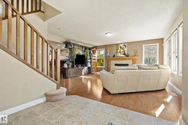 Living room with a large white sectional sofa, fireplace, and decorative plants - 351 Griesbach School Rd Nw, Edmonton