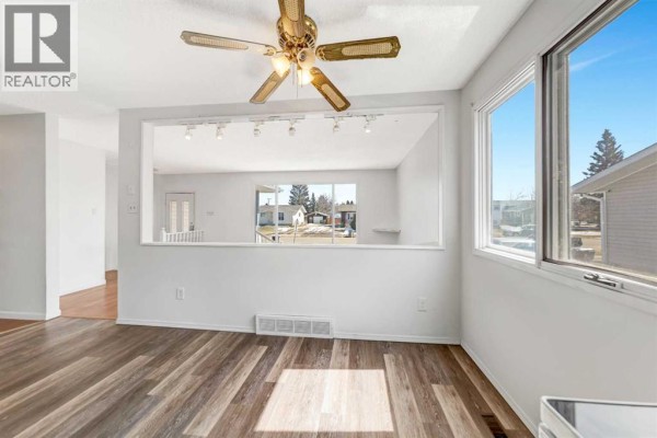 View into the dining area from the living room, showing laminate flooring and a large window. - 3510 57 Avenue, Lloydminster