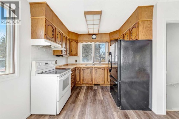 Kitchen with white appliances, wood cabinets, tile backsplash, and laminate flooring. - 3510 57 Avenue, Lloydminster