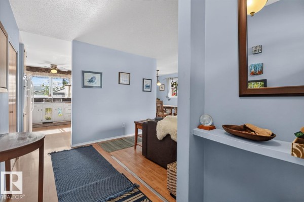 Interior view from hallway to living room, dining room, and kitchen with light blue walls. - 3511 106 Av Nw, Edmonton