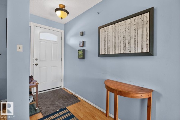 Entryway with a white door, wood floor, light blue walls, and a console table. - 3511 106 Av Nw, Edmonton