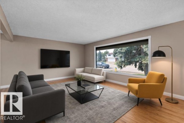 Living room with a large window facing the street, hardwood floors, and multiple seating areas. - 3511 73 St Nw, Edmonton