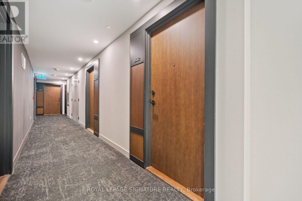 Apartment building hallway with patterned carpet, dark wood doors, and grey walls. - 3512 - 4065 Confederation Parkway, Mississauga