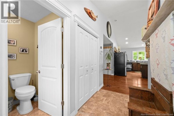 Interior hallway with a toilet in a small adjacent room, white double doors, and view of kitchen. - 3515 Route 530, Grande Digue