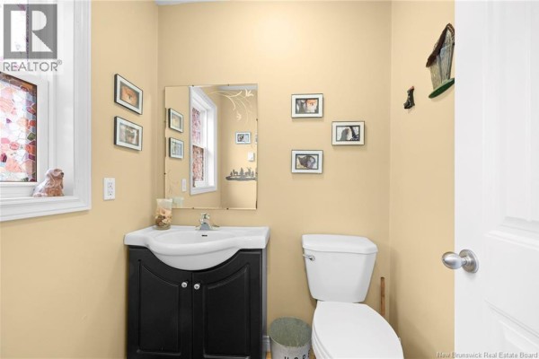 Powder room with a sink, vanity, mirror, toilet, and yellow walls with framed pictures. - 3515 Route 530, Grande Digue