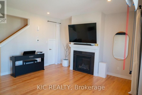 Living room with hardwood floors, a gas fireplace, a large television, and a digital piano. - 352 Appalachian Circle, Ottawa