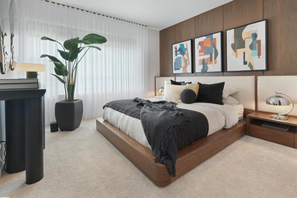 Bedroom with a king-size bed, wood accent wall, and large window with sheer curtains. - 352 Stiles Wy, Leduc