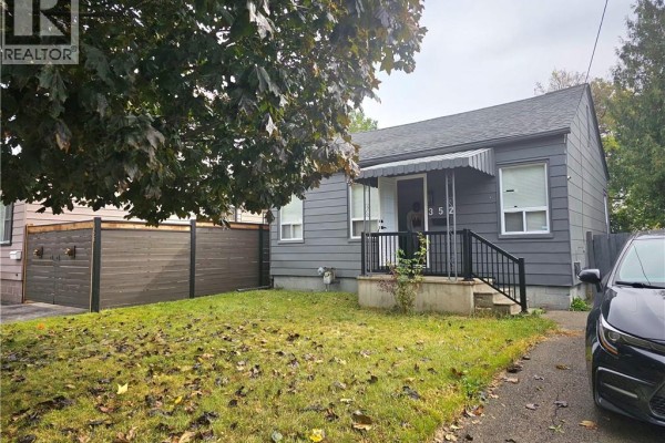 Front view of the grey house at 352 Weir Street N, Hamilton, with a paved driveway and grass lawn. - 352 Weir Street N, Hamilton