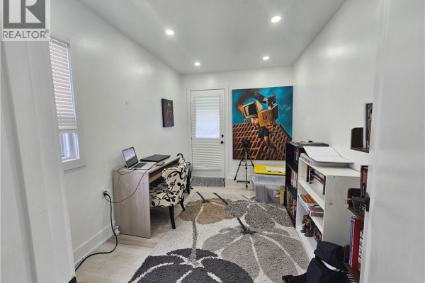 Home office with a desk, chair, bookshelves, and a large colorful painting above a door. - 352 Weir Street N, Hamilton