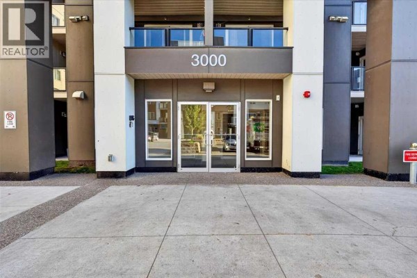 Entrance to apartment building with glass doors, concrete walkway, and building number 3000. - 3520, 4641 128 Avenue Ne, Calgary