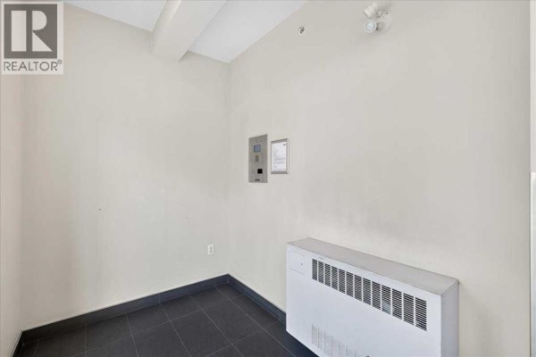 Interior utility closet with white heating unit, electrical panel, and dark tiled floor. - 3520, 4641 128 Avenue Ne, Calgary