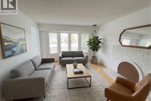 Living room with two grey sofas, a leather armchair, coffee table, rug, and potted plant. - 3520 Broadway Street, Richmond