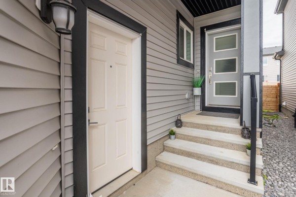 Close-up view of the duplex entrances, showing a cream door and a modern glass door with steps. - 3523 5a Av Sw, Edmonton
