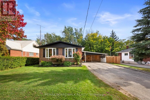 Wide angle exterior view of a brick bungalow with a paved driveway and a large green lawn. - 353 Churchill Road E, Prescott