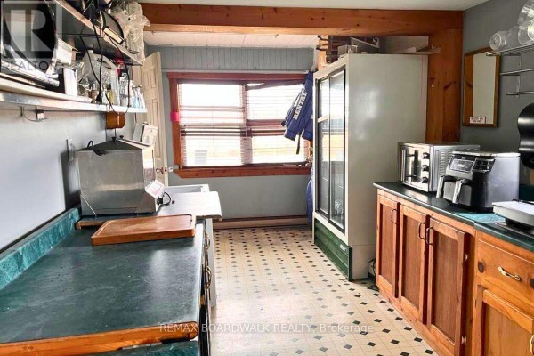 Commercial kitchen with green counters, wooden cabinets, and a large white cooler. - 353 County Rd 5 Road, Athens