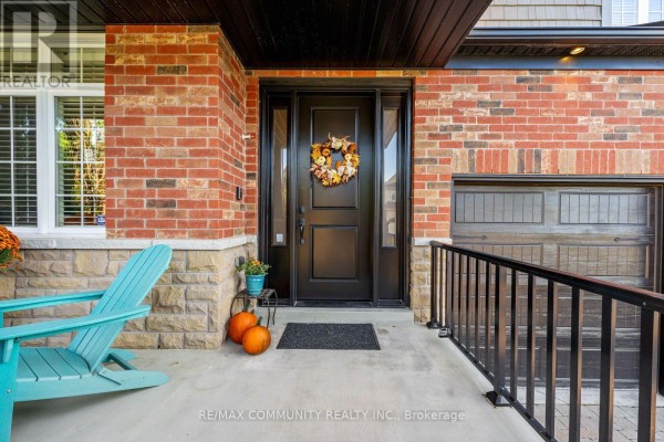 Front door with a wreath, surrounded by brick and a light blue Adirondack chair. - 353 Shipway Avenue, Clarington
