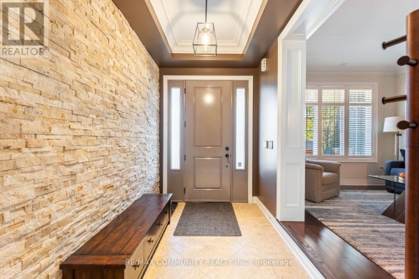 Entrance hall with a stone accent wall, bench, and view into the living room. - 353 Shipway Avenue, Clarington