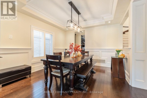 Dining room with a dark wood table and bench, overlooking a window and staircase. - 353 Shipway Avenue, Clarington