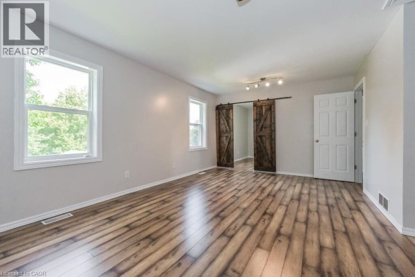 Interior view of living room with grey walls, laminate flooring, and ceiling fan. - 353 Wellington Street E, Mount Forest