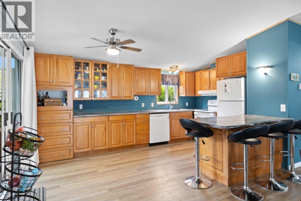 Hallway with laundry machines, storage cabinets, and view into dining area. - 3535 Casorso Road Unit# 62, Kelowna