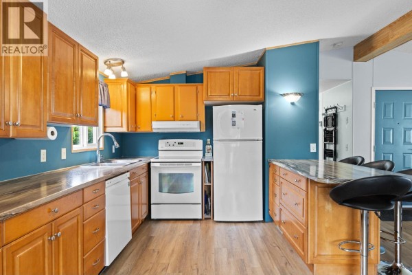 Exterior of a light beige mobile home with a covered porch and driveway. - 3535 Casorso Road Unit# 62, Kelowna