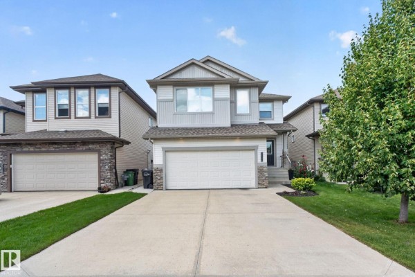Front exterior of a modern two-story house with gray siding and stone accents during the day. - 3536 Claxton Cr Sw Sw, Edmonton