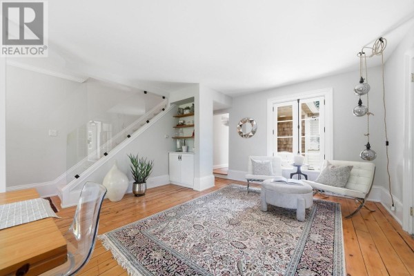 Living room with wooden floors, a patterned rug, and white furniture. - 354 College Street, Cobourg
