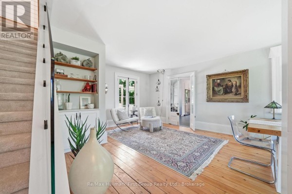 Living room with wooden floors, a patterned rug, and a large oil painting on the wall. - 354 College Street, Cobourg