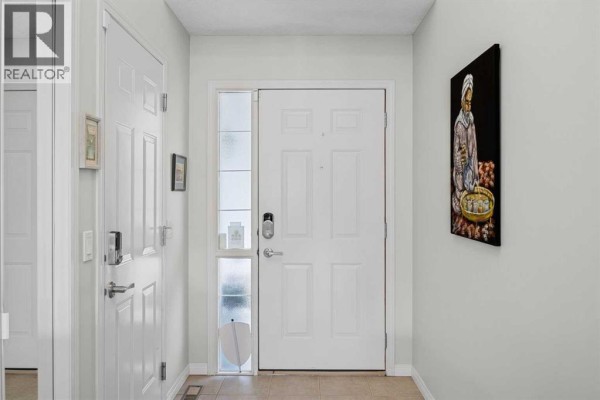 Bright interior entryway with white doors, a glass sidelight, and artwork on the wall. - 354 West Creek Springs, Chestermere