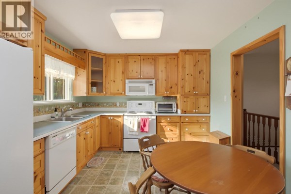 Kitchen with light wood cabinets, white appliances, and a dining area to the side. - 3543 Devon Road, Port Coquitlam