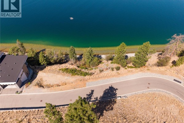 Aerial view of the shoreline and water at 3548 Arrowroot Drive with a boat on the lake. - 3548 Arrowroot Drive, Kelowna