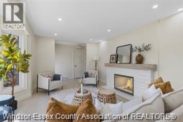 Living room fireplace with stone surround, cream walls, and seating area with chairs. - 3549 Ouellette, Windsor