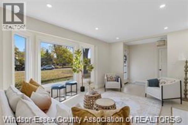 Living room with large window, sofa, fireplace, and doorways leading to other rooms. - 3549 Ouellette, Windsor